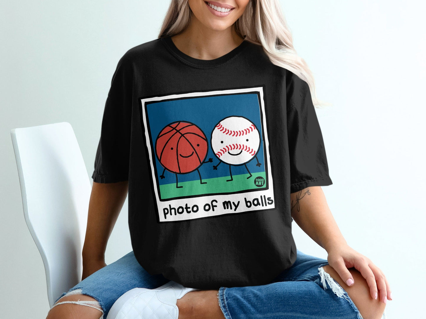 Black t-shirt with cartoon basketball and baseball holding hands.