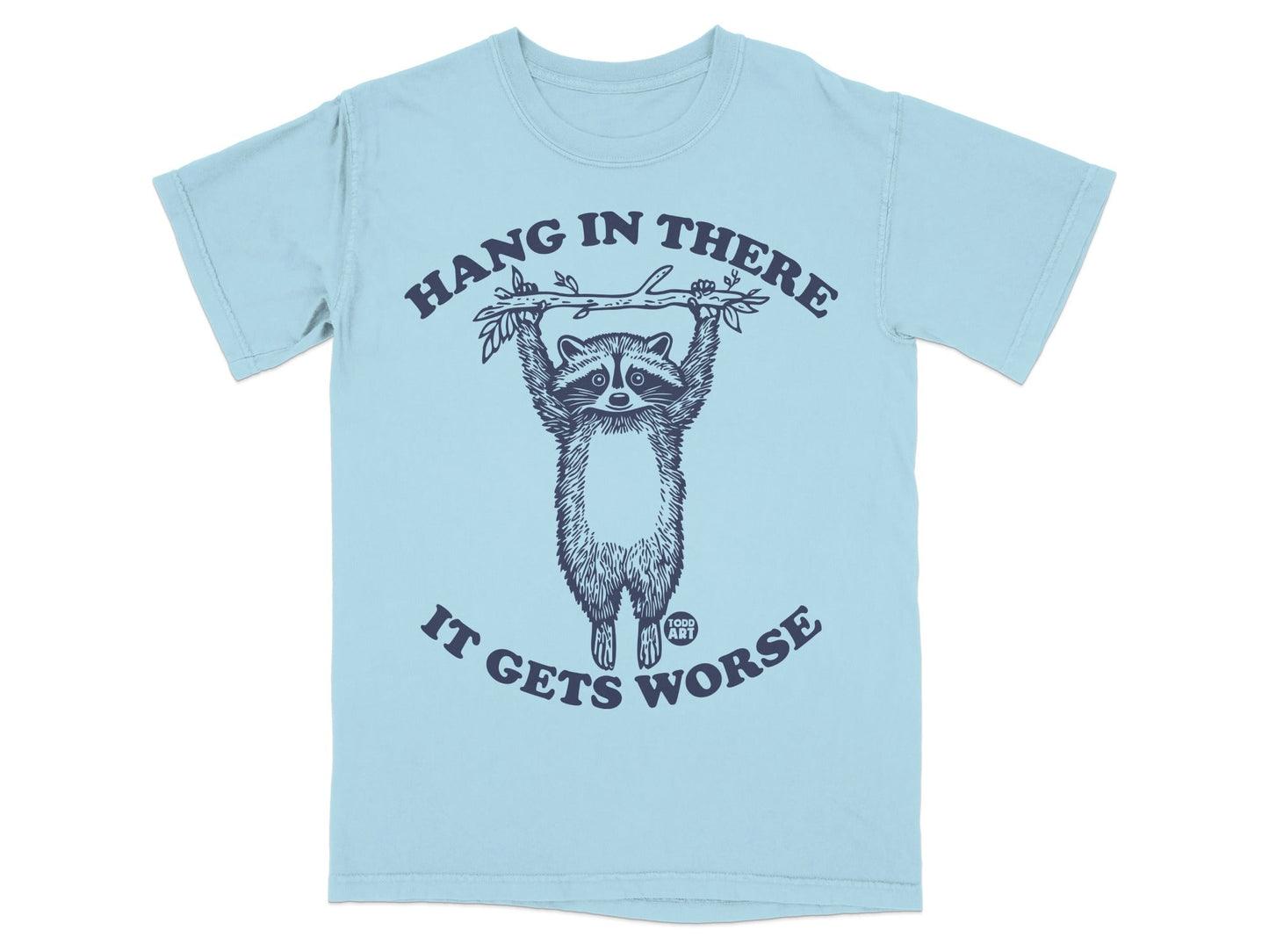 Light blue t-shirt with raccoon hanging from branch, text "Hang in There It Gets Worse".