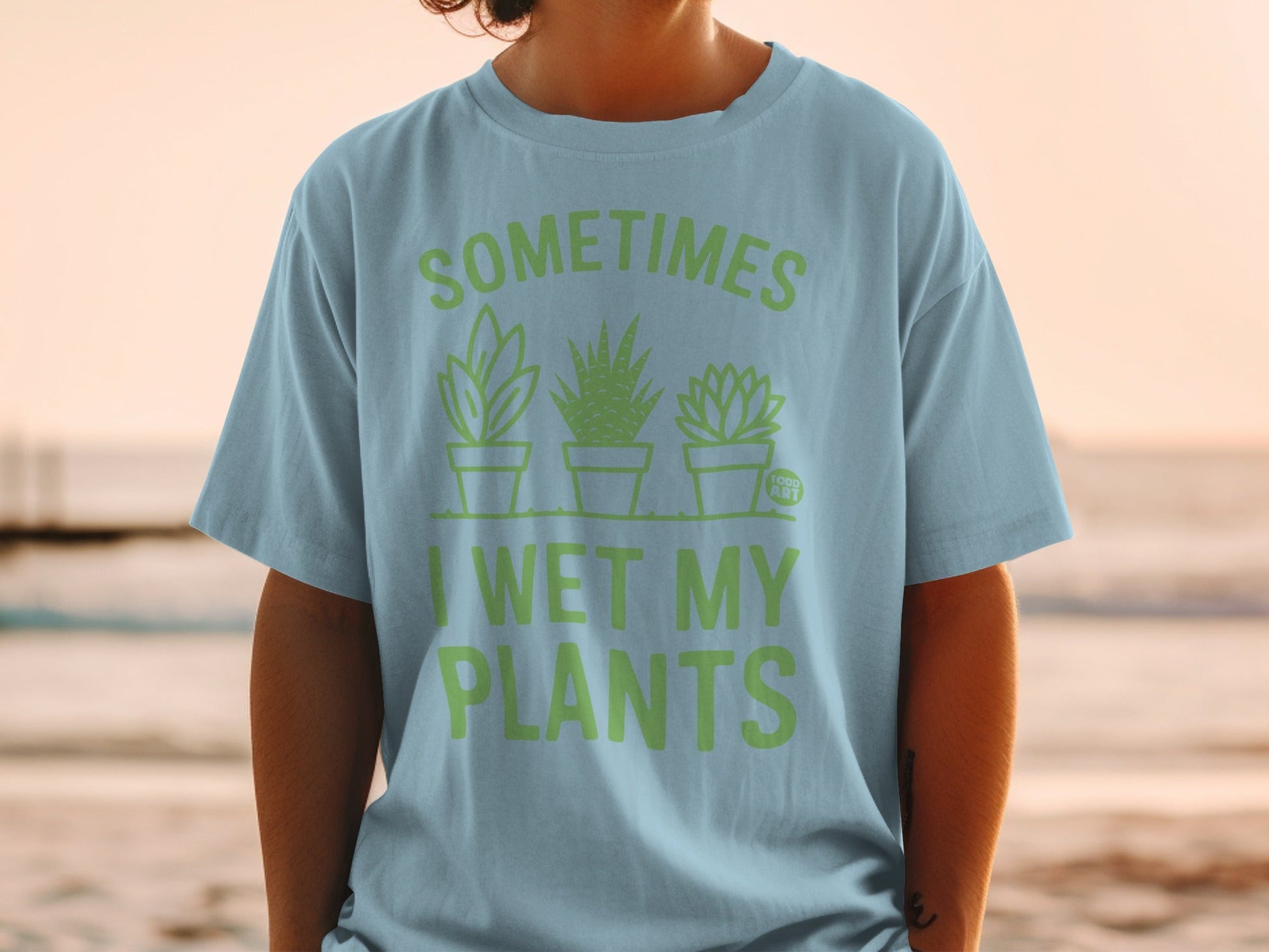 Light blue t-shirt with "SOMETIMES I WET MY PLANTS" and three potted plants.