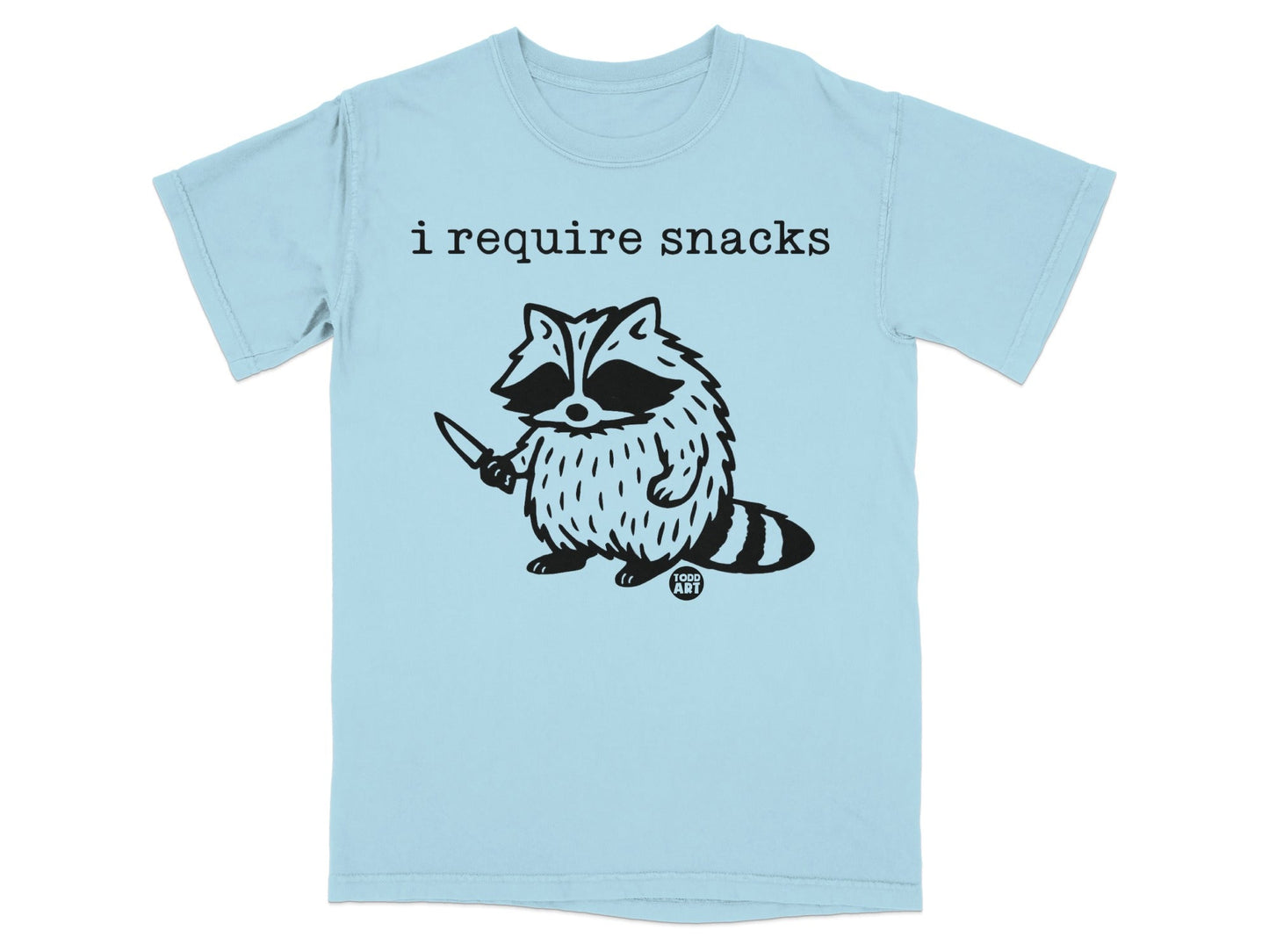 Light blue t-shirt with black graphic of a raccoon holding a knife and text "i require snacks".