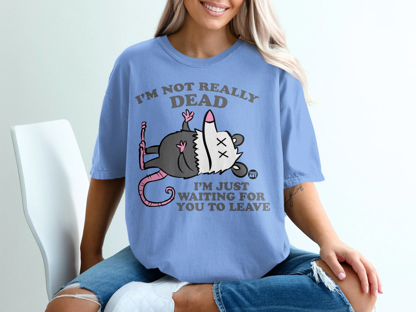 Blue t-shirt with cartoon opossum saying "I'm not really dead I'm just waiting for you to leave."