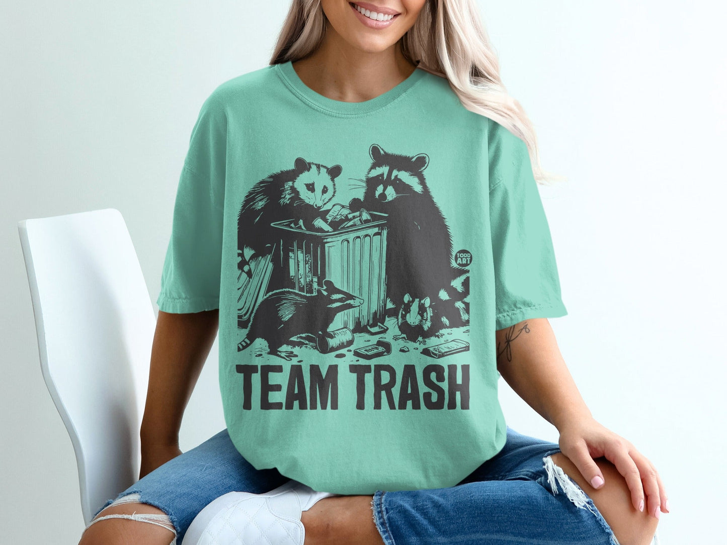 T-shirt featuring a raccoon and opossum by trash can with "TEAM TRASH" text.