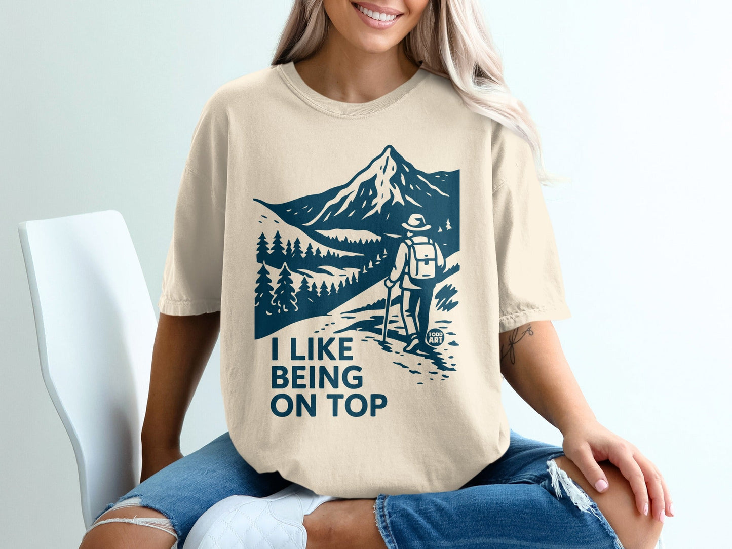 Cream t-shirt with "I LIKE BEING ON TOP" and mountain graphic.
