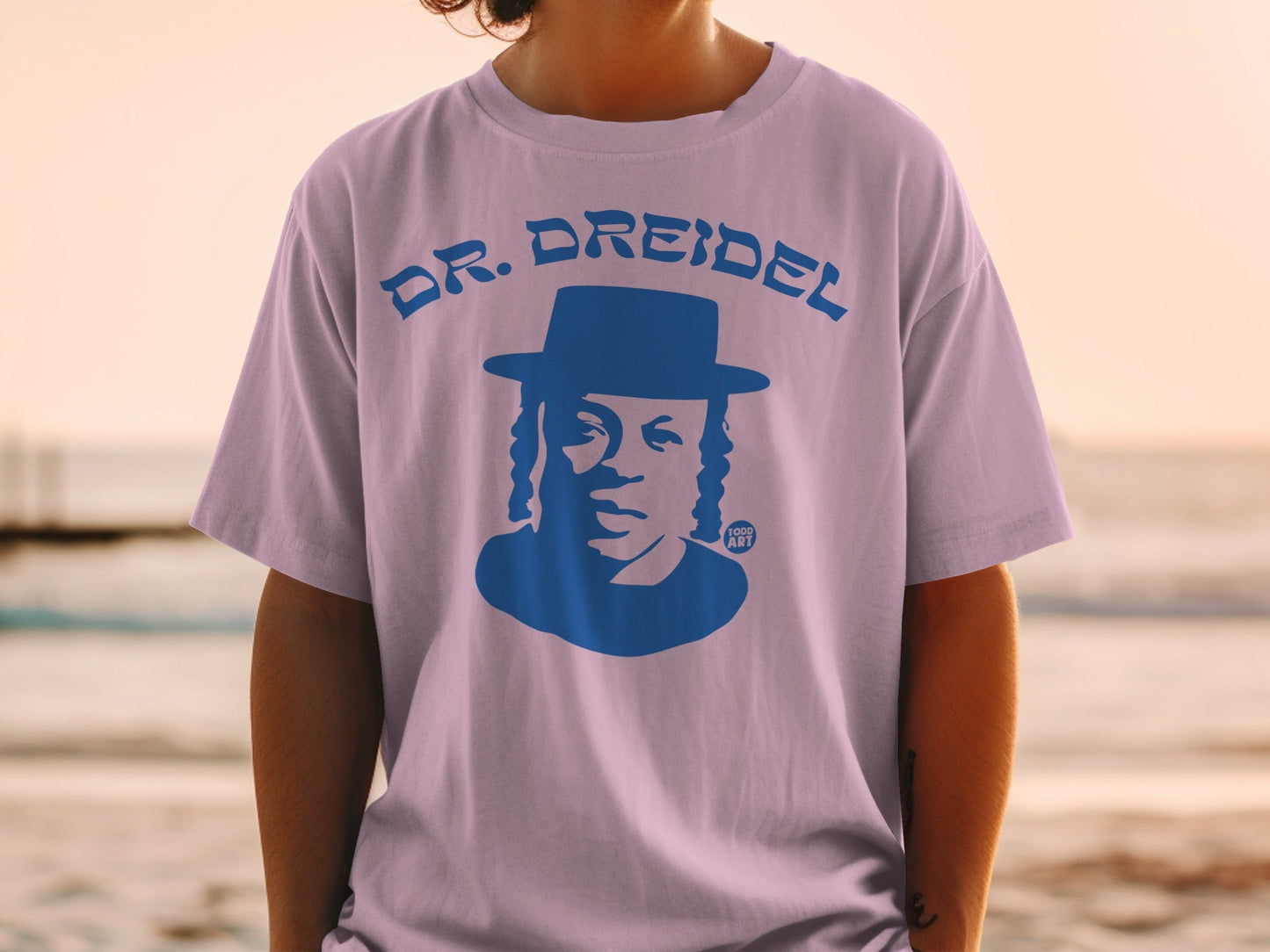 Purple t-shirt with blue graphic of a man in a hat and text "DR. DREIDEL"