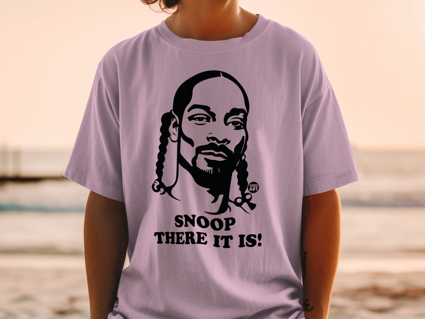 Snoop Dogg portrait on a light purple t-shirt with "SNOOP THERE IT IS!" text.
