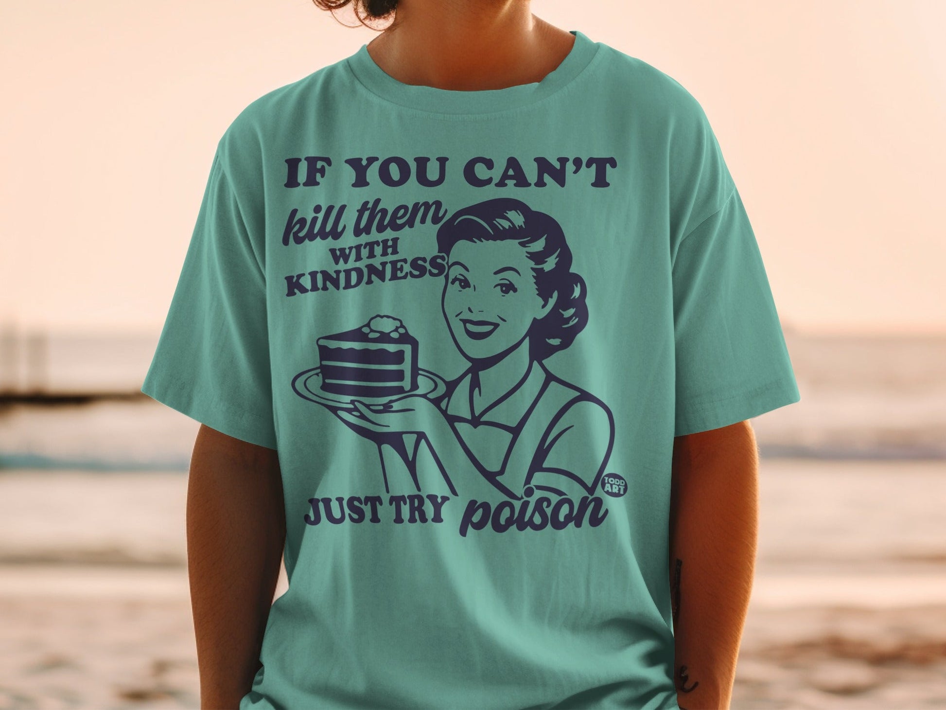 Teal t-shirt with retro woman holding cake and text "If you can't kill them with kindness, just try poison".