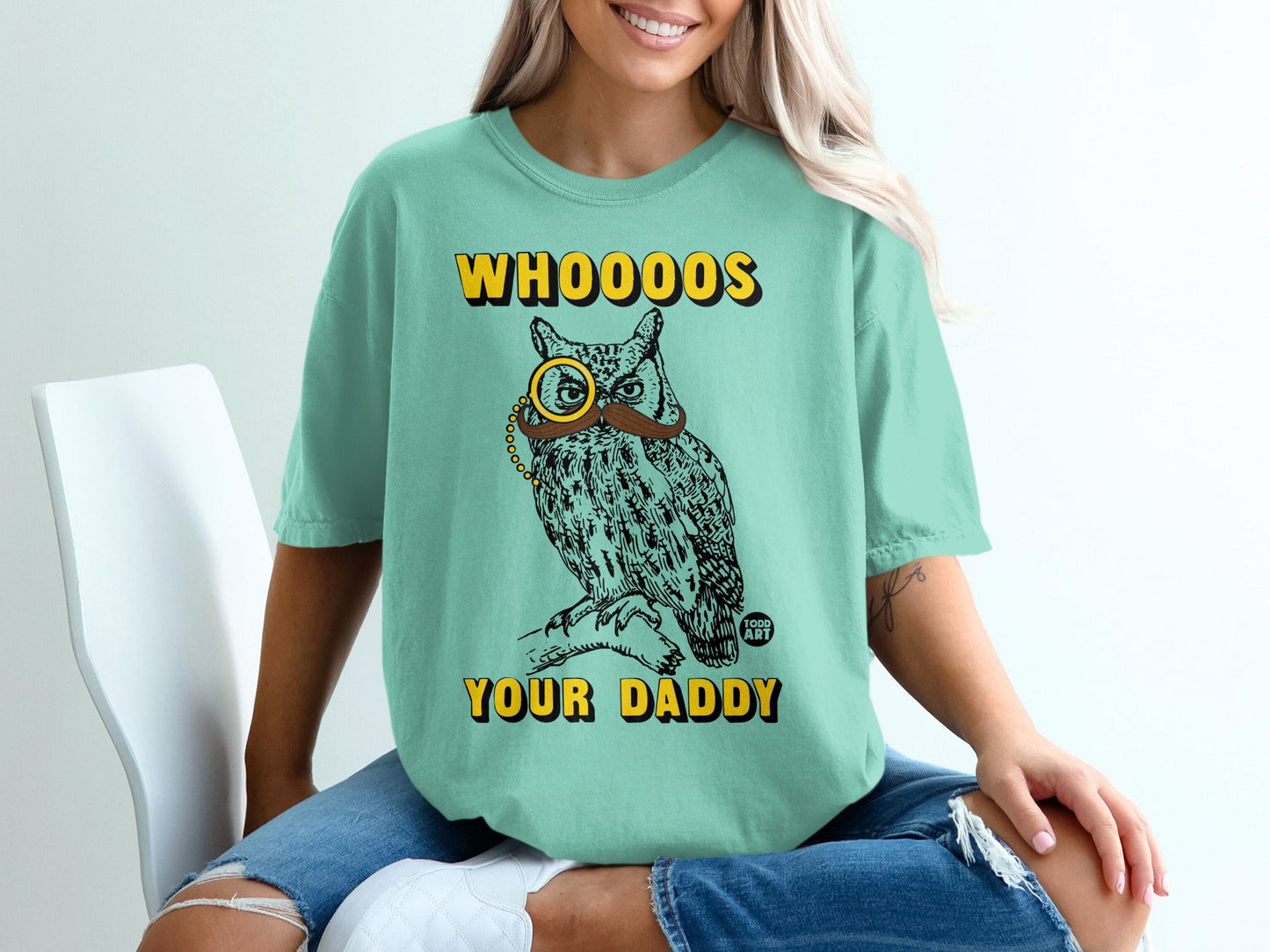 Mint t-shirt with illustration of an owl wearing a monocle and mustache, text "Whooo's Your Daddy?".