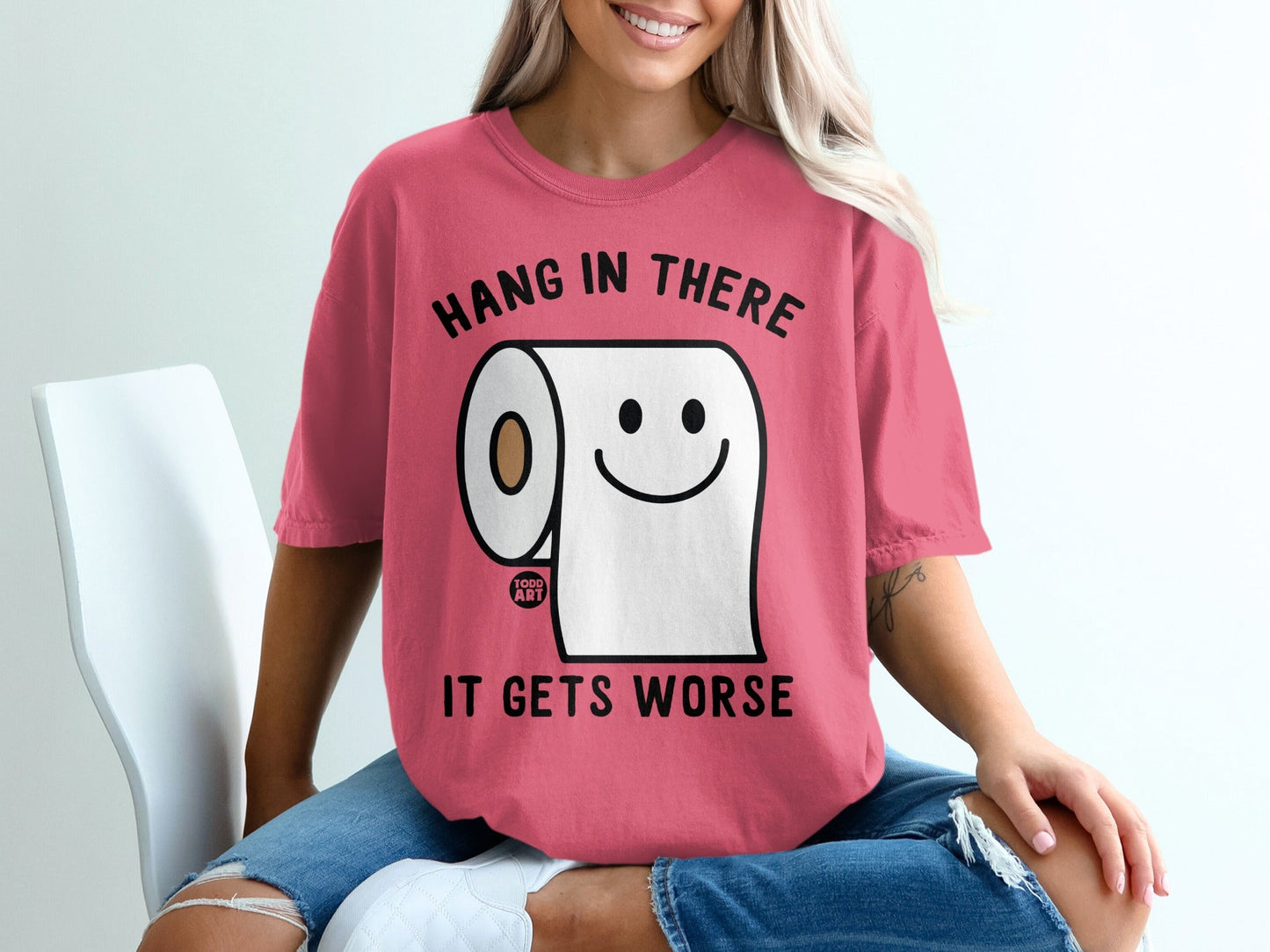 Pink t-shirt with toilet paper roll smiling, "Hang in there it gets worse".