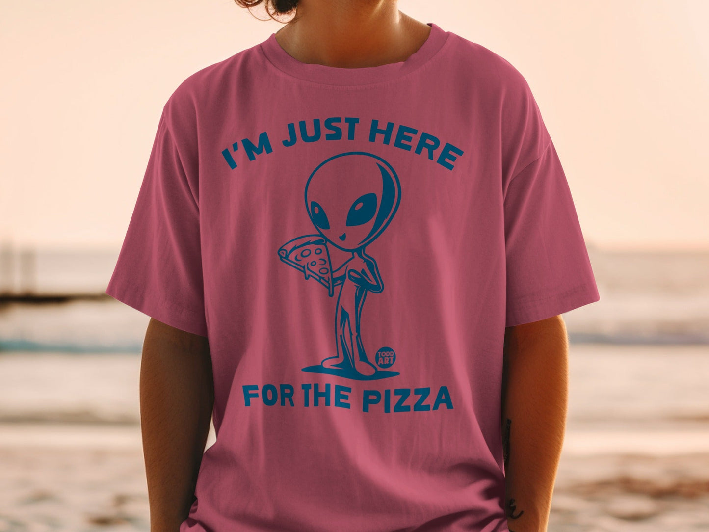 Pink t-shirt with blue alien holding pizza and text "I'M JUST HERE FOR THE PIZZA".