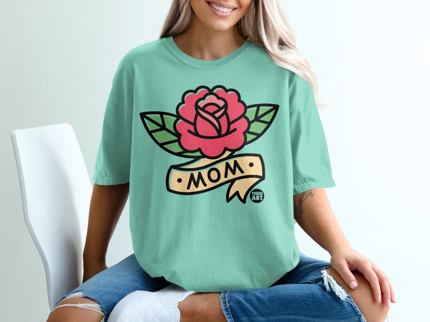 Teal t-shirt with a pink rose on a banner, "MOM" text.