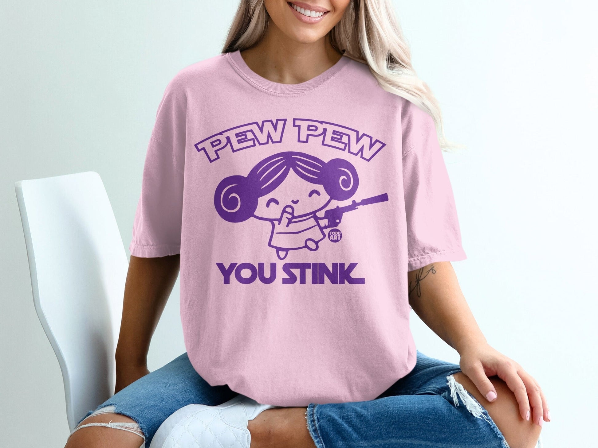 Pink t-shirt with "Pew Pew You Stink" text and cartoon girl holding a gun.
