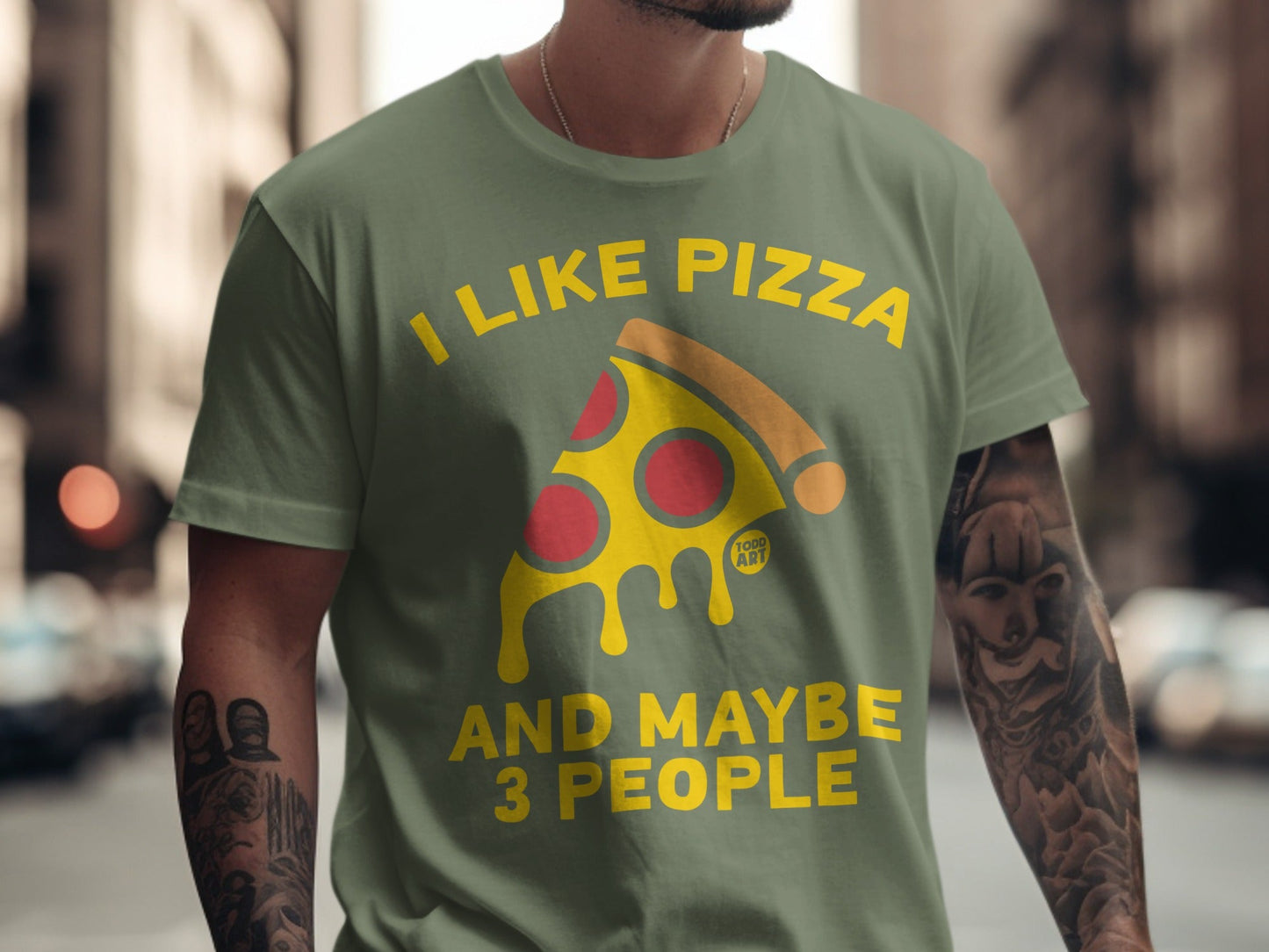 Green t-shirt with "I like pizza and maybe 3 people" text and pizza slice graphic.