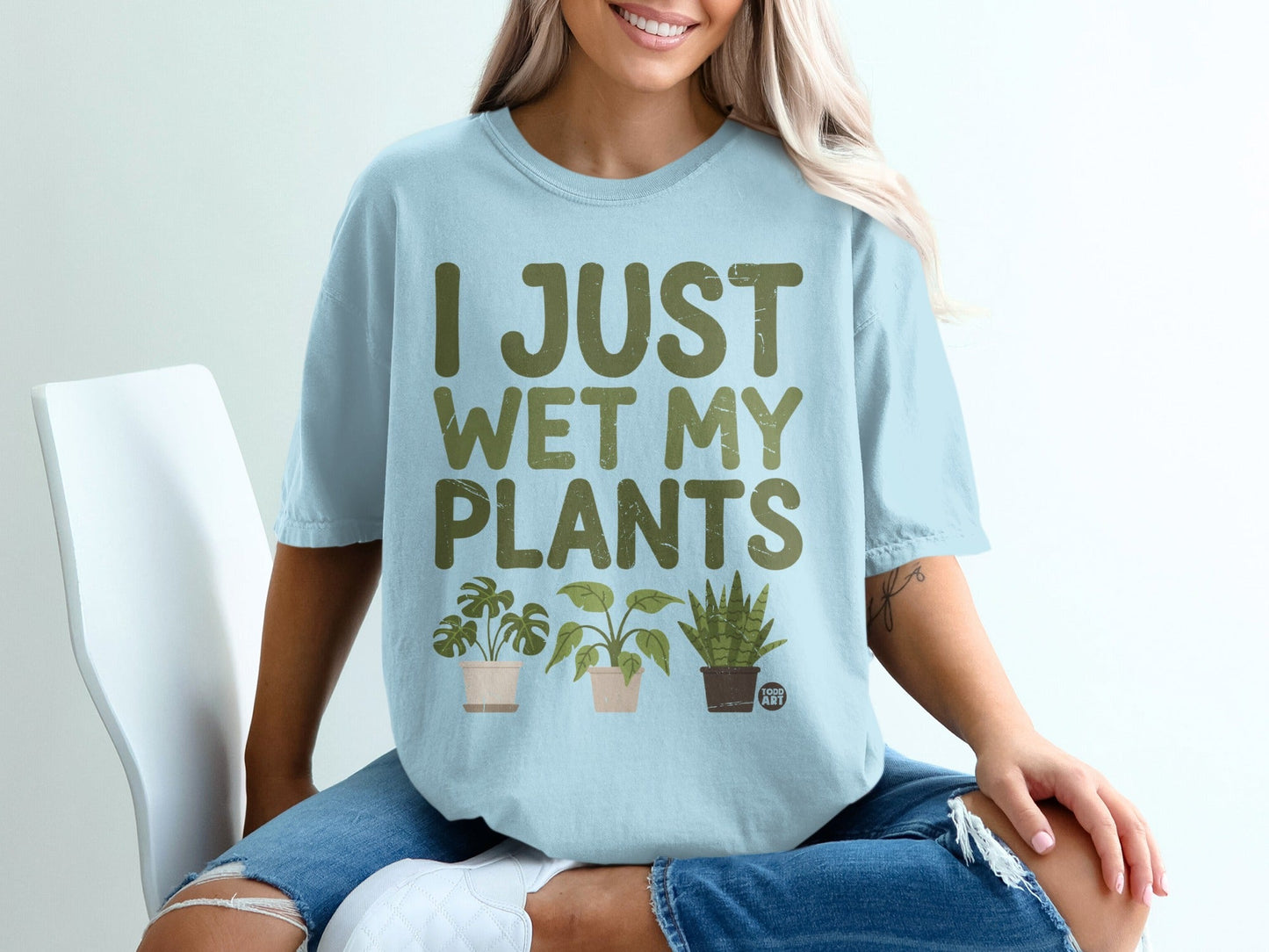 Light blue t-shirt with green text "I JUST WET MY PLANTS" and potted plants.