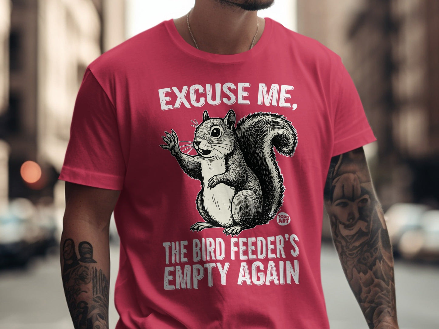 T-shirt with graphic of a squirrel saying "Excuse me, the bird feeder's empty again."
