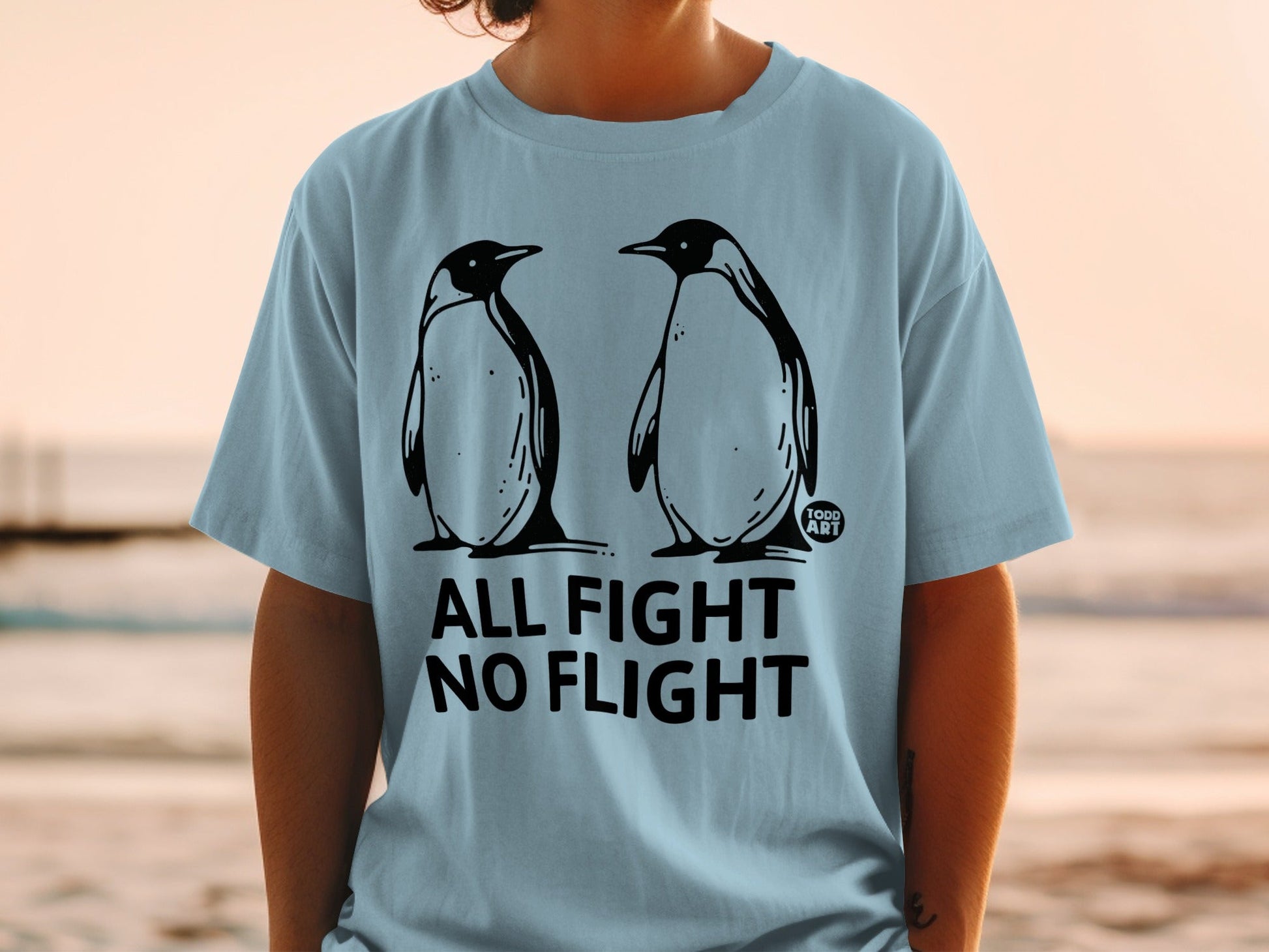 Light blue t-shirt with two penguins and "ALL FIGHT NO FLIGHT" text.