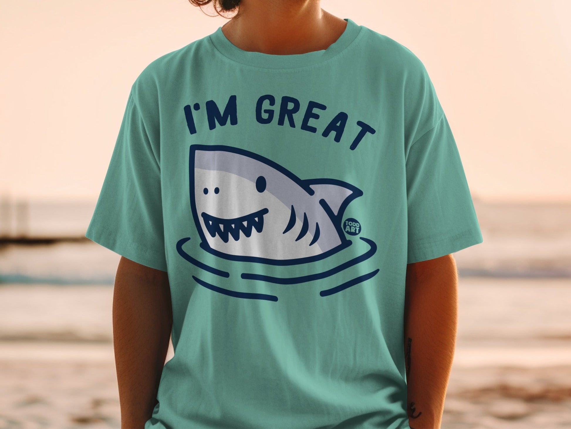 Teal t-shirt with "I'm Great" text and cartoon shark illustration.