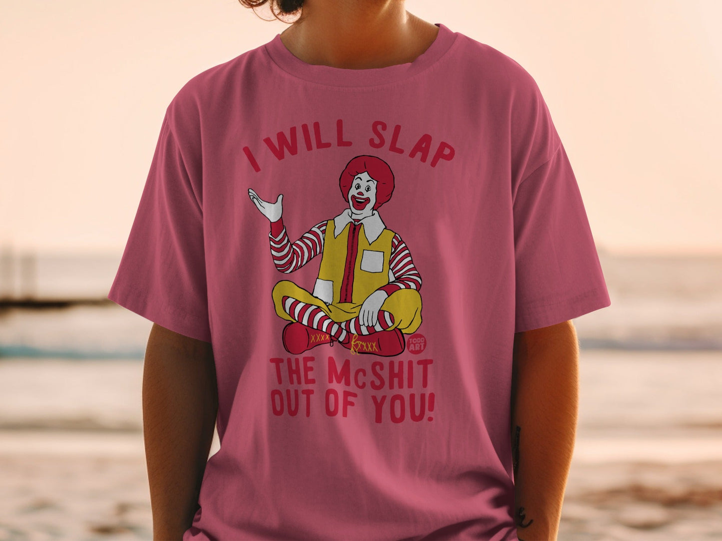 Ronald McDonald sitting cross-legged on a t-shirt with a warning.