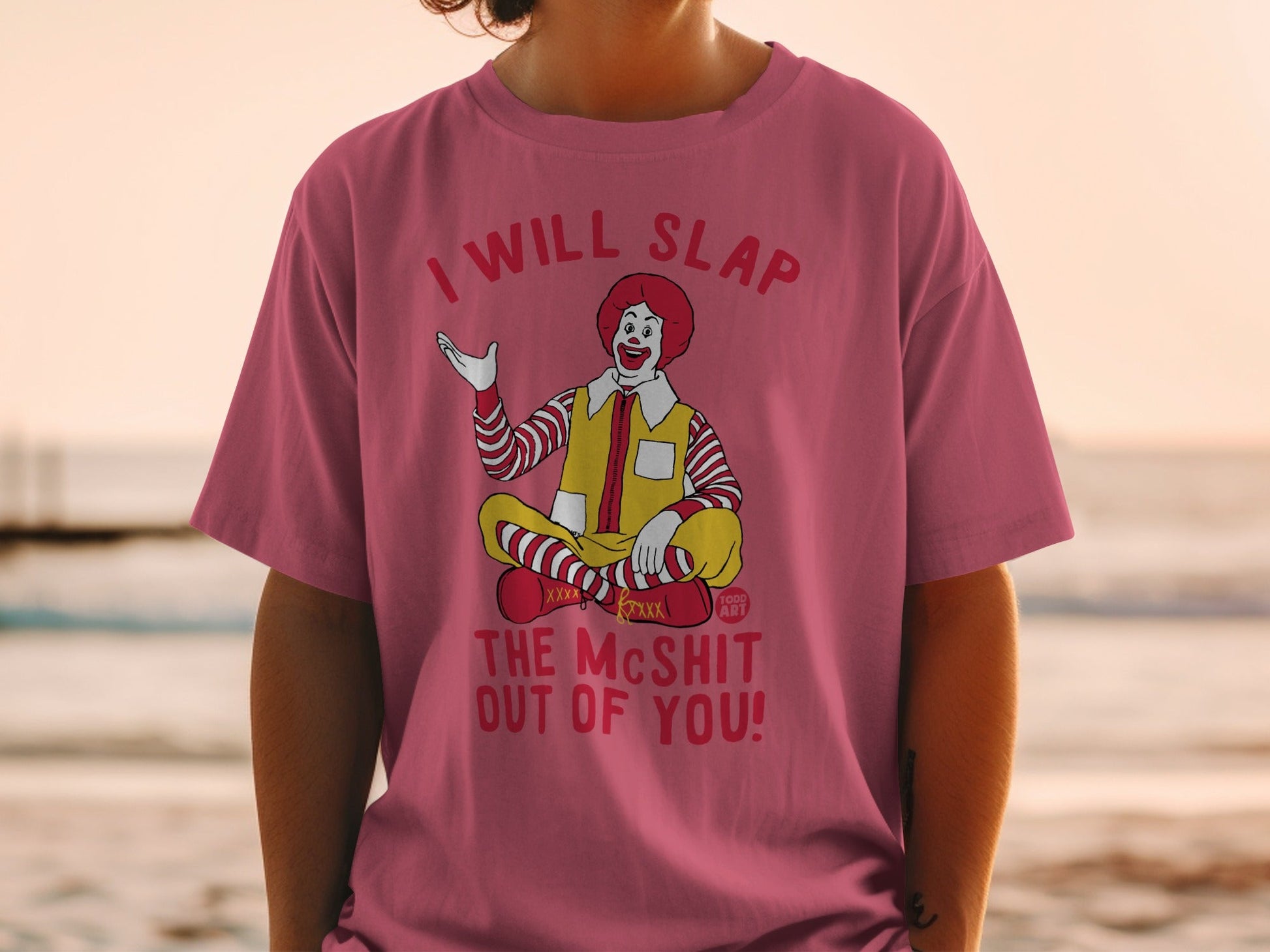 Ronald McDonald sitting cross-legged on a t-shirt with a warning.