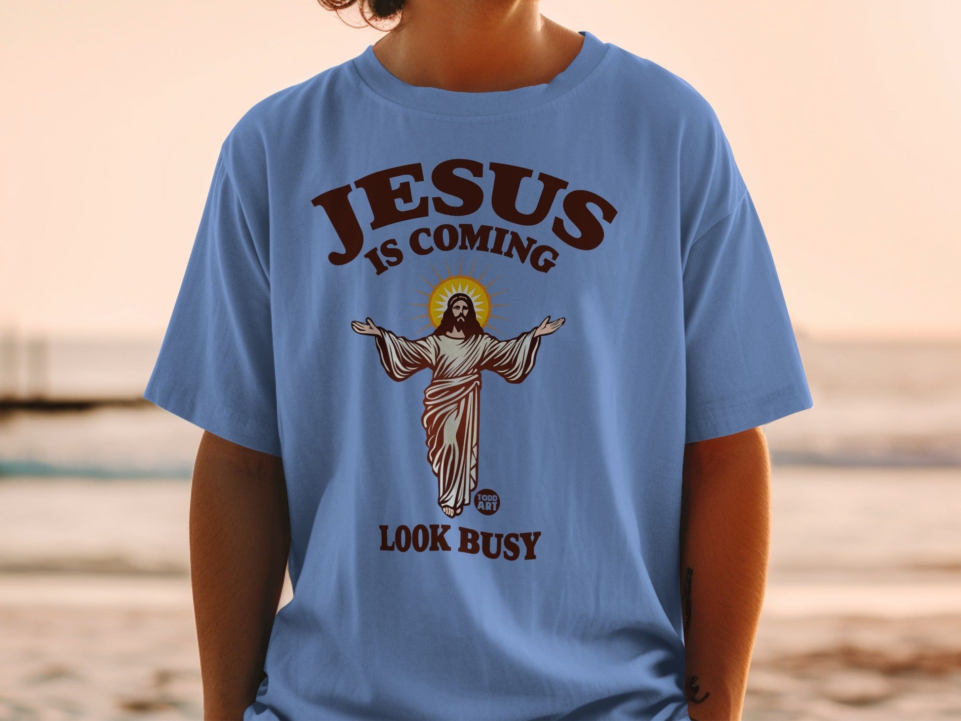 Jesus is coming, look busy text on a blue t-shirt with Jesus illustration.