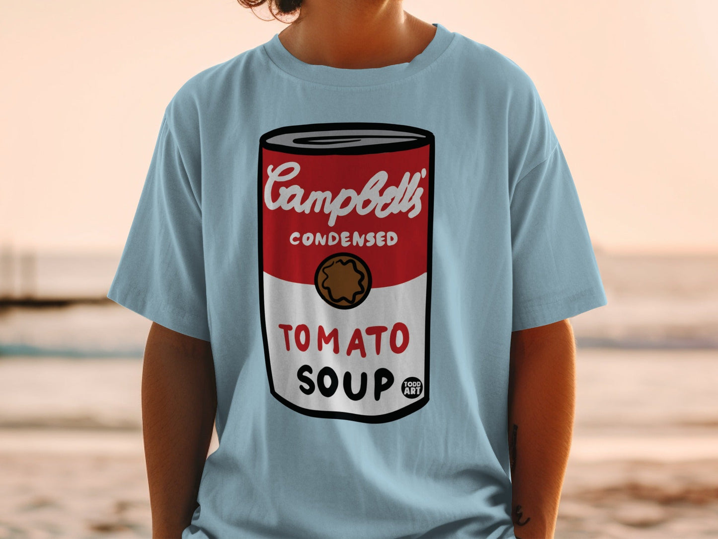 Light blue t-shirt featuring Campbell's Condensed Tomato Soup can graphic.