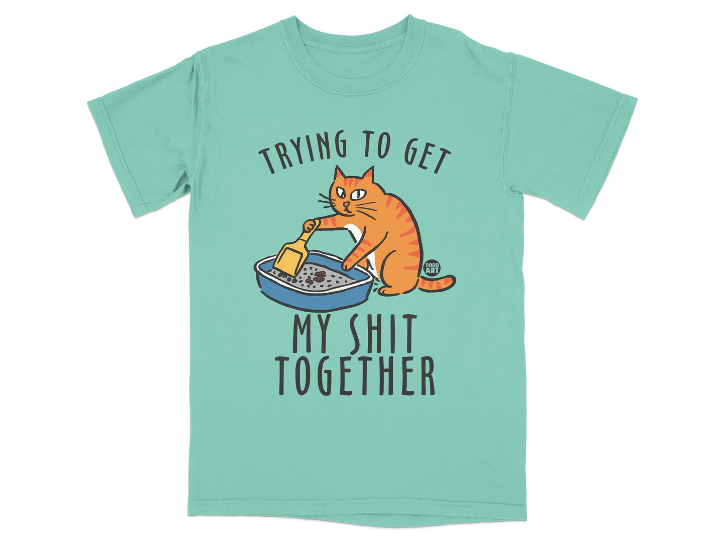 T-shirt with cartoon cat scooping litter box and text "Trying to get my shit together".
