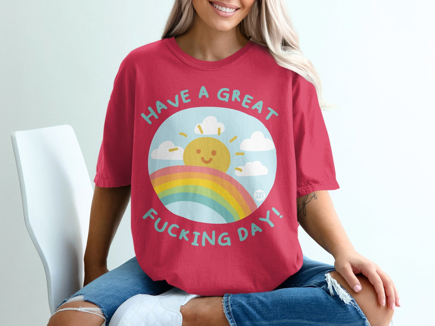 Red t-shirt with a graphic featuring a smiling sun, rainbow, and clouds.