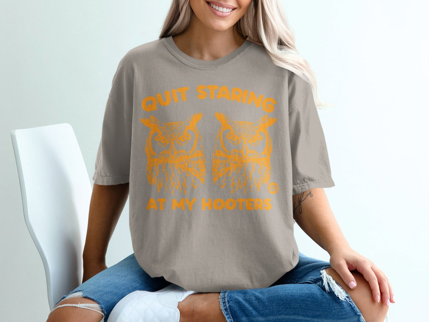 Tan t-shirt with orange graphic of two owls and text "QUIT STARING AT MY HOOTERS".