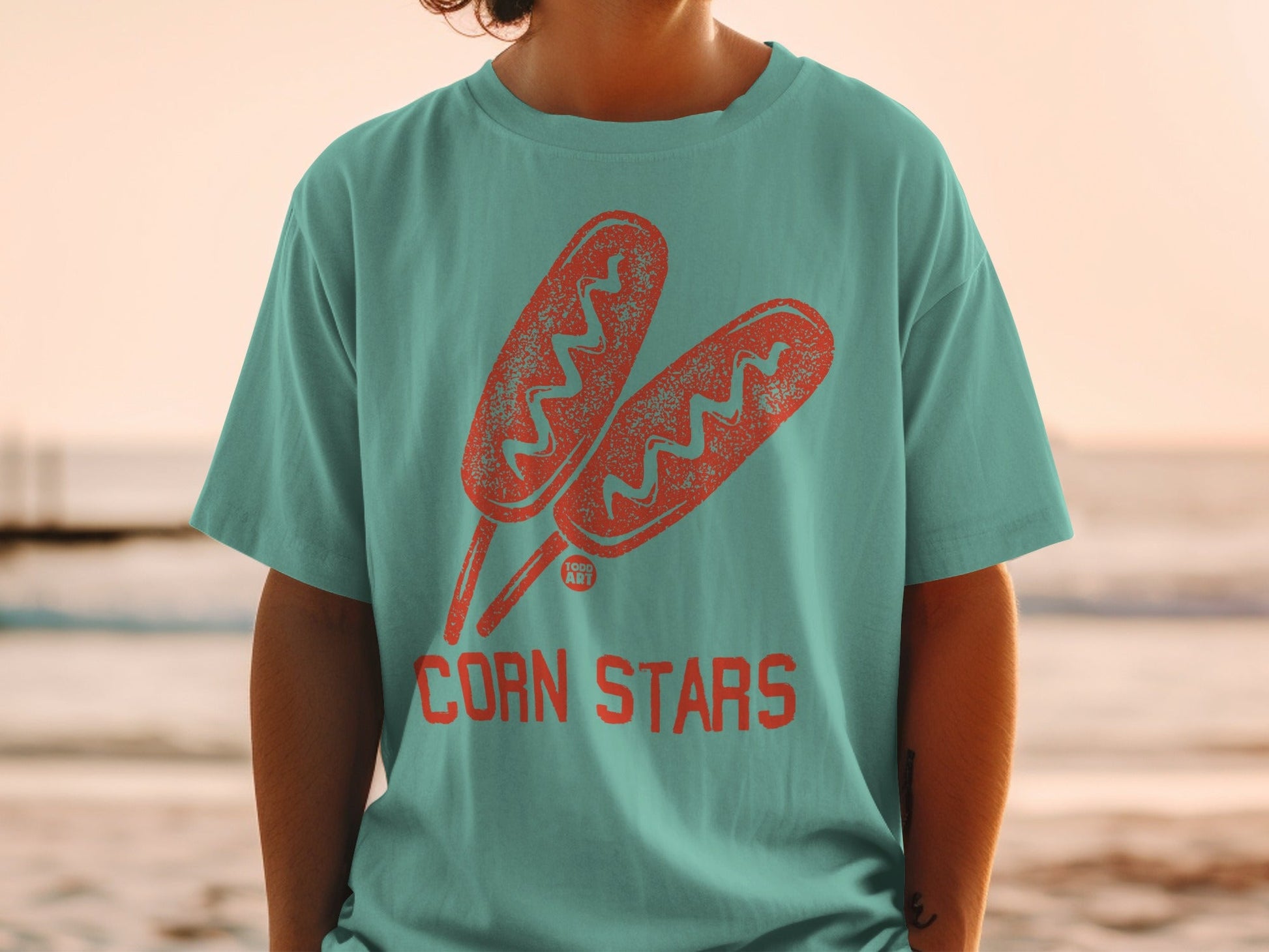 Corn dogs with "Corn Stars" text on a teal t-shirt.