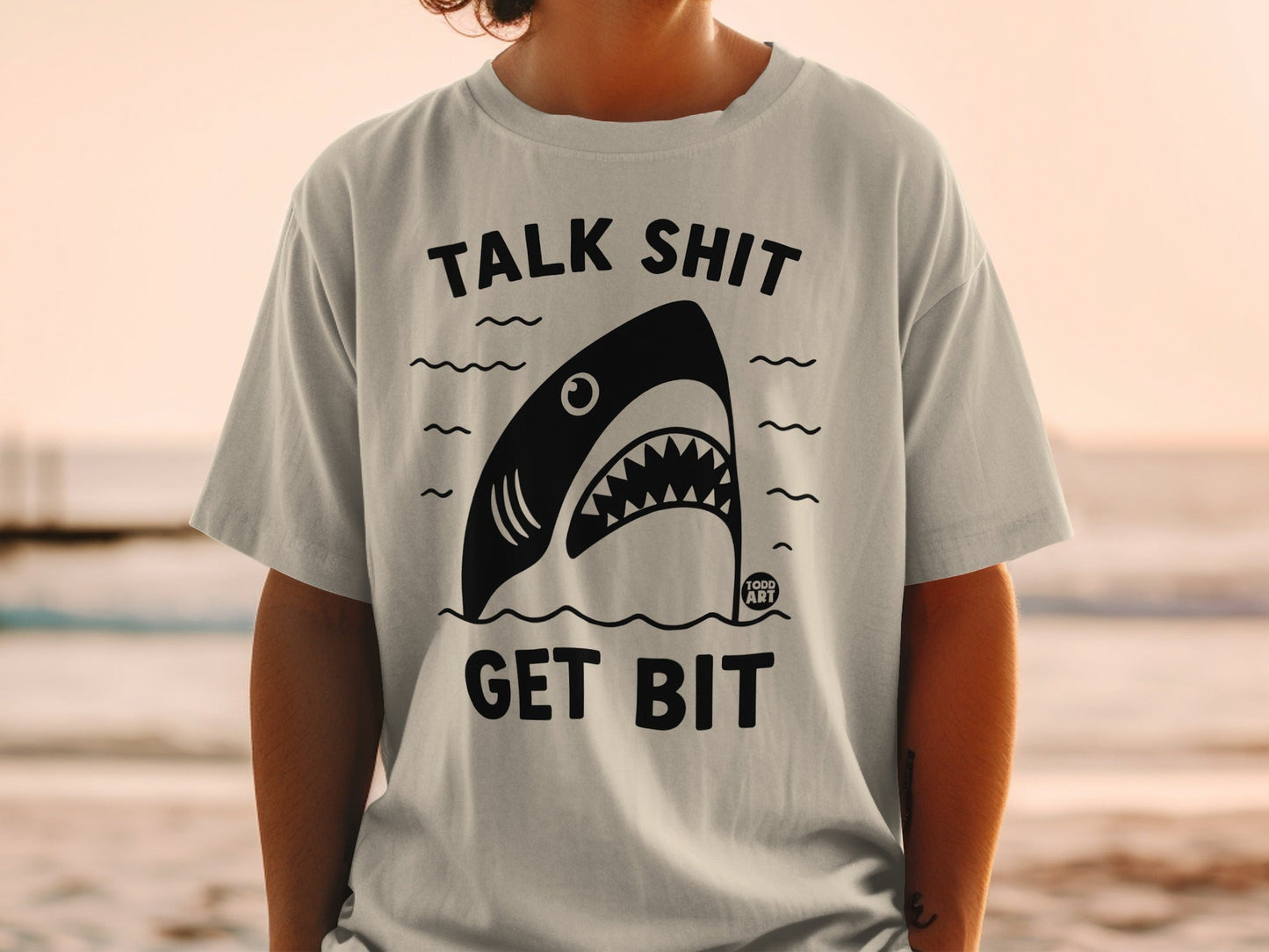 Black and white shark graphic on a t-shirt with text "TALK SHIT GET BIT."