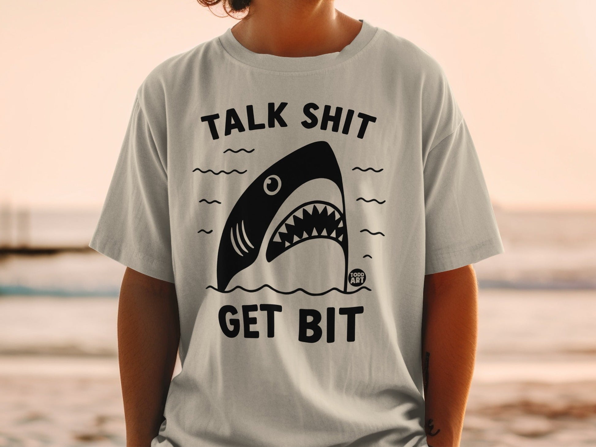 Black and white shark graphic on a t-shirt with text "TALK SHIT GET BIT."