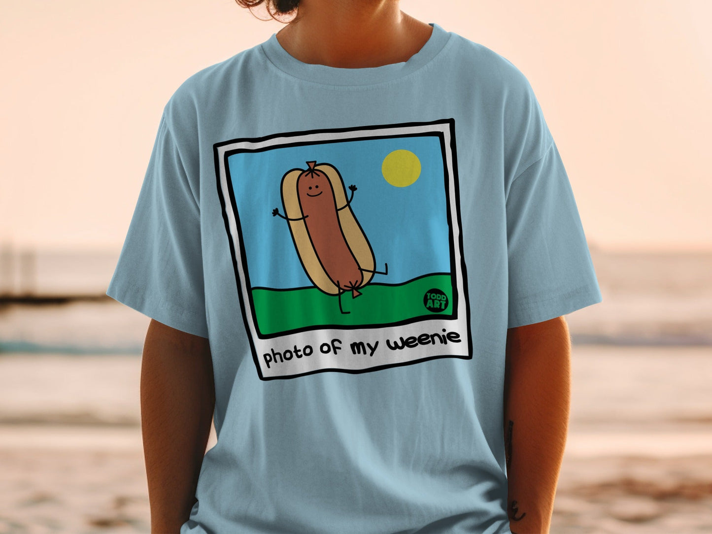 Cartoon hot dog in sunglasses on a grassy hill under a yellow sun, "photo of my weenie" text.