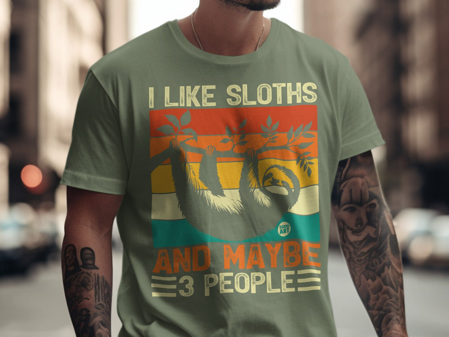 Green t-shirt with "I like sloths and maybe 3 people" text and sloth graphic.