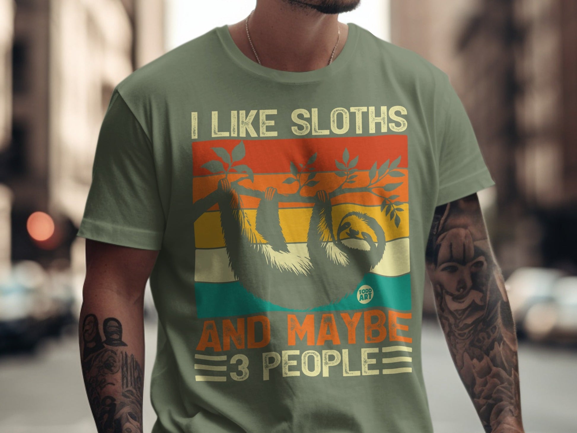 Green t-shirt with "I like sloths and maybe 3 people" text and sloth graphic.