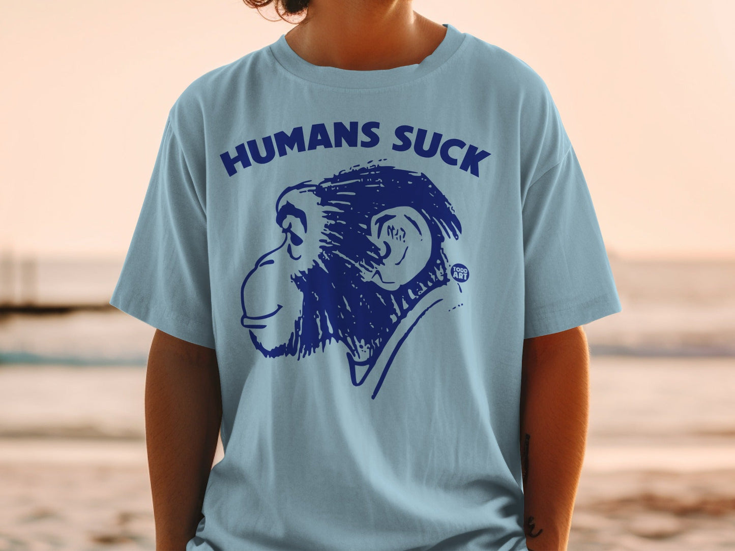 Light blue t-shirt with blue monkey graphic and text "HUMANS SUCK."