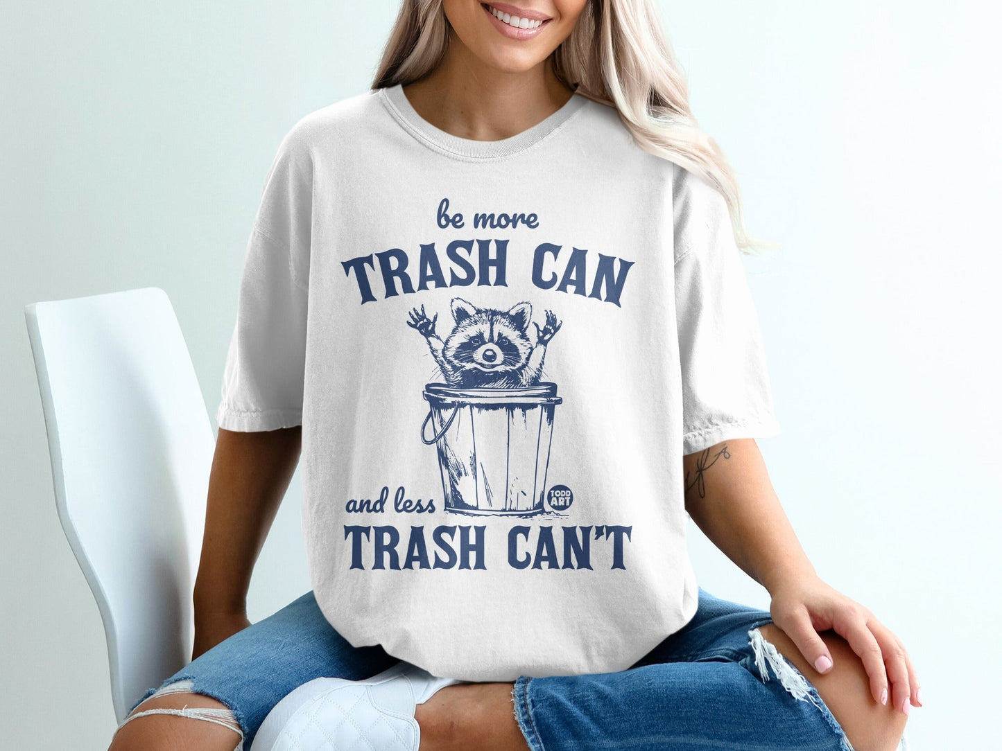 White t-shirt with "be more trash can and less trash can't" graphic.