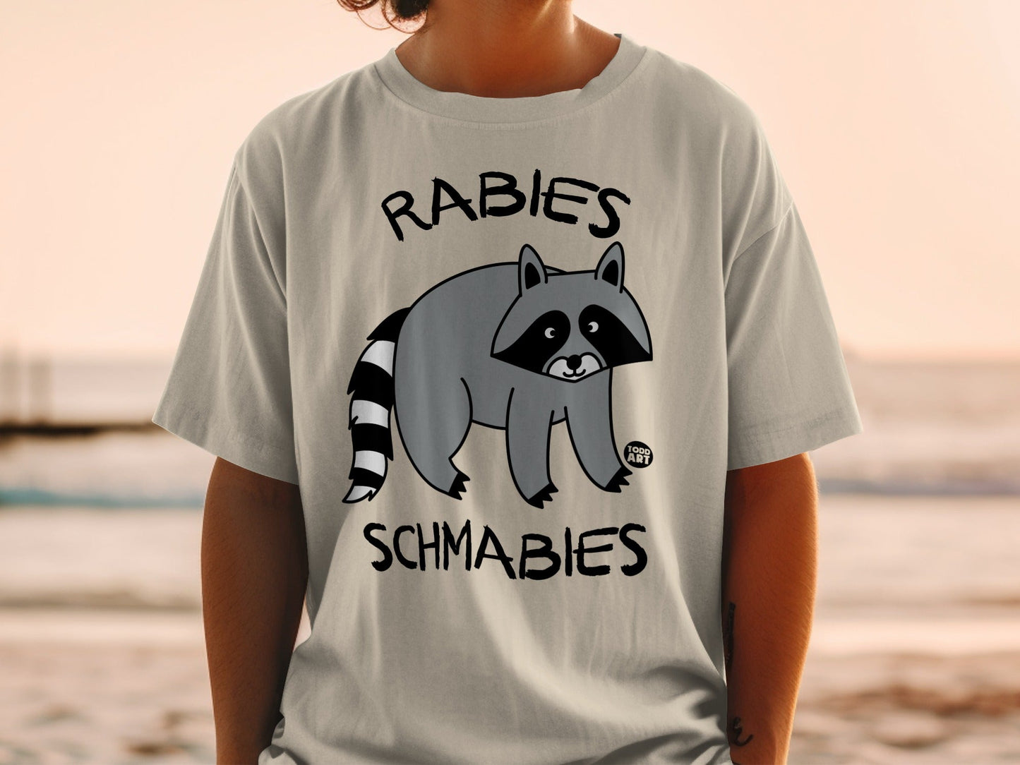 T-shirt with raccoon graphic and text "Rabies Schmabies."