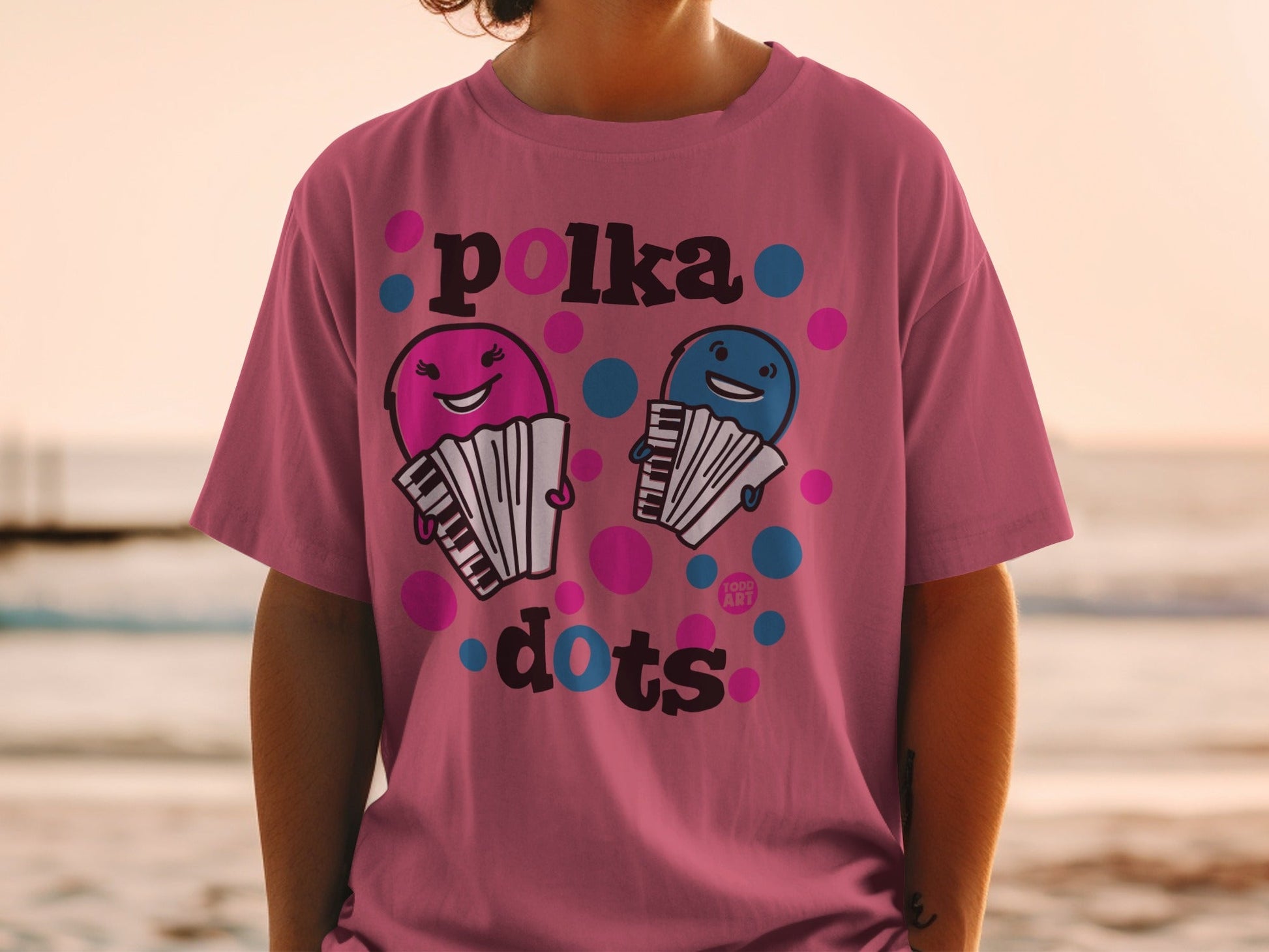 Pink t-shirt with cartoon accordions and "Polka Dots" text.