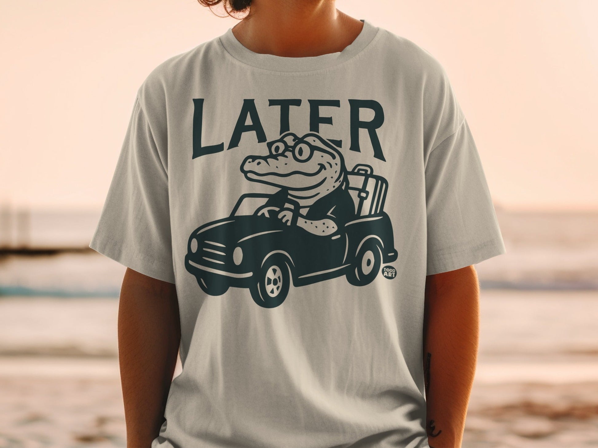 T-shirt graphic of alligator driving car, "LATER" text.