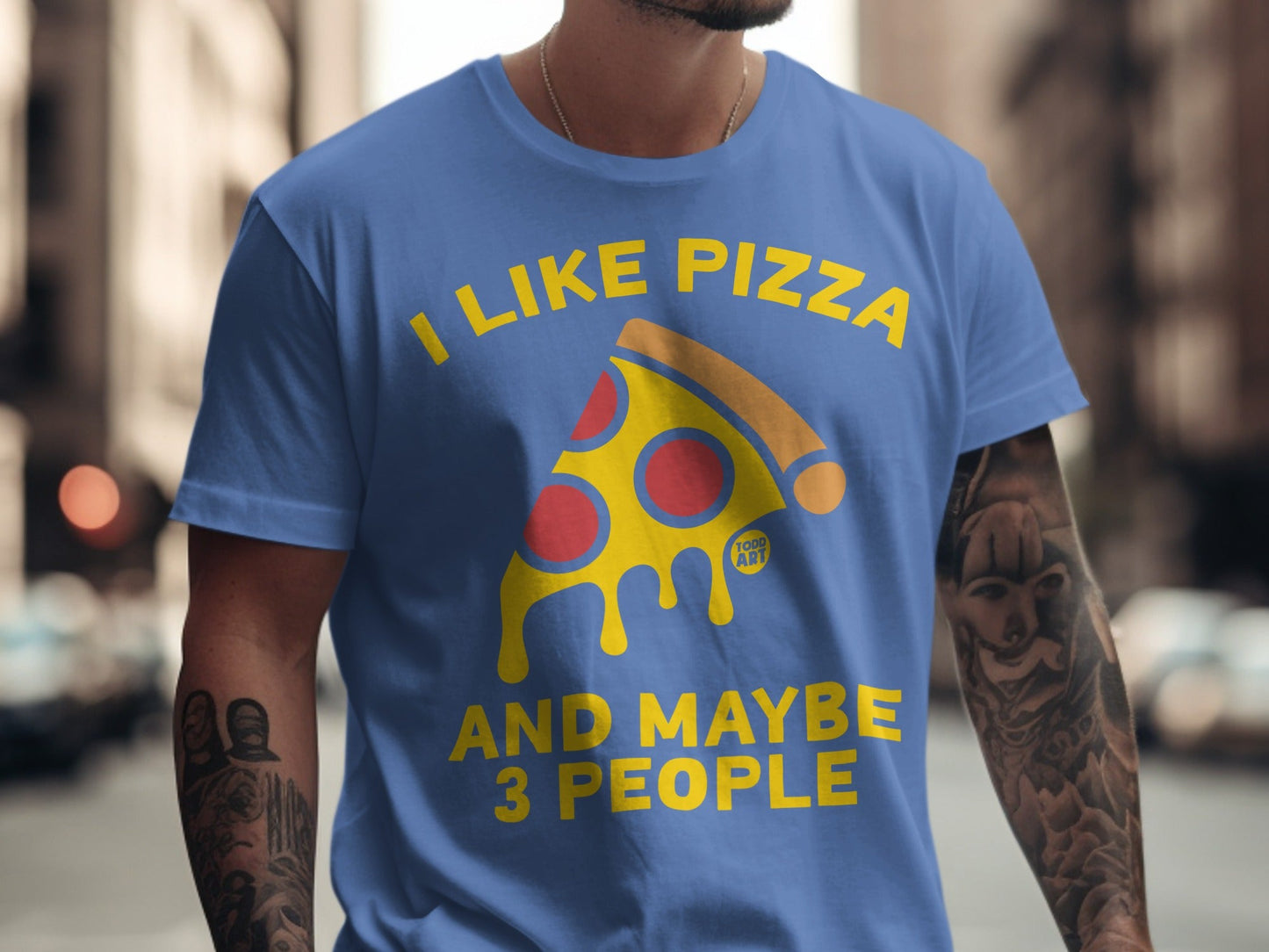 Blue t-shirt with yellow text "I LIKE PIZZA AND MAYBE 3 PEOPLE" and pizza slice graphic.